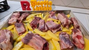 Costine e patate condite con olio, aglio, sale, pepe e rosmarino